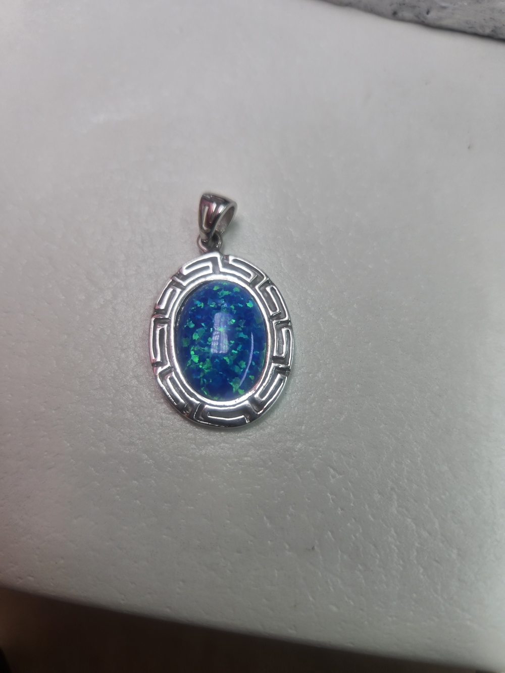 sterling silver pendant featuring a vibrant lab-created blue opal stone surround